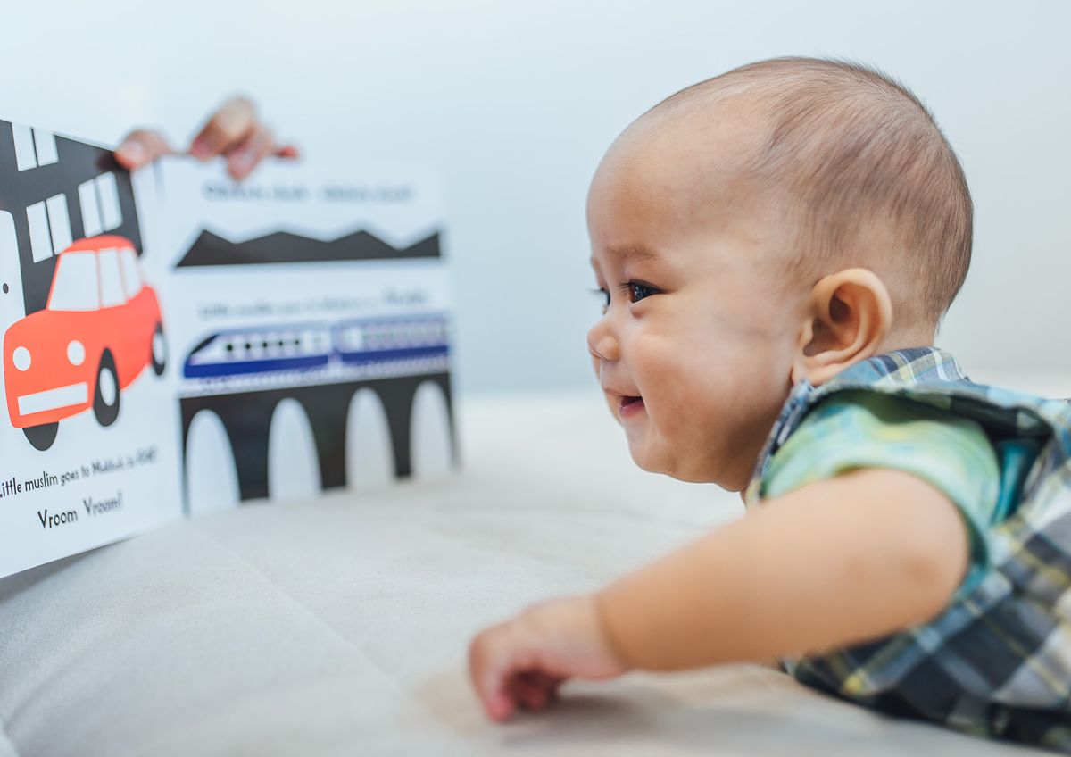 Bayi meniarap tersenyum melihat buku kontras tinggi Oliek Books